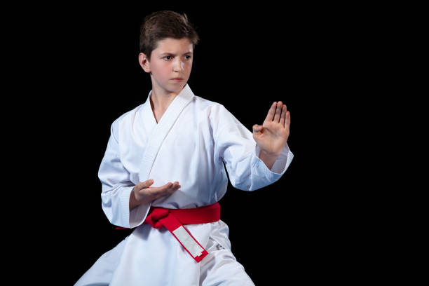 Young boy dressed in a white karate kimono with red belt