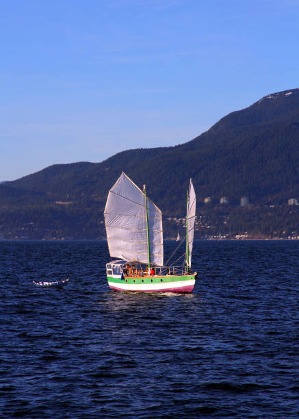 Junk on the Blue Sea A junk in harbor in English Bay, Vancouver, Canada. beach english bay vancouver skyline stock pictures, royalty-free photos & images