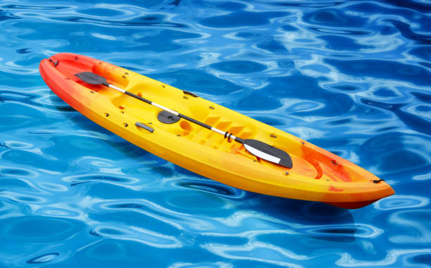 istock colse up orange yellow plastic kayak with paddle on the blue water 985359450