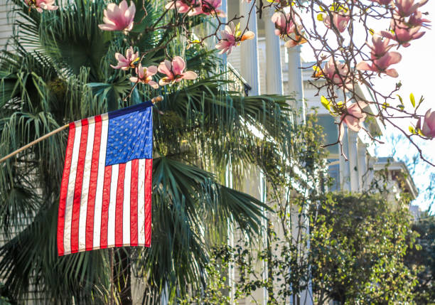 American flag flies from a front porch in scenic New Orleans. Cherry blossoms blooming and sun shining on a beautiful day in the American south