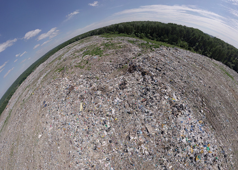 Aeral pamoramic view to a huge garbage dump located within the city, which consists of many wastes polluting the Nature and the environment