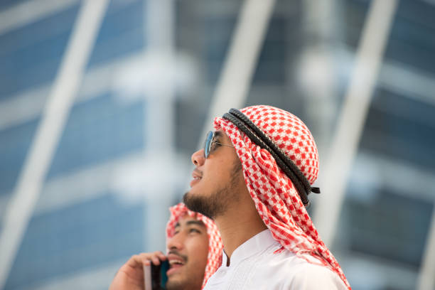 bello uomo d'affari arabo sta guardando fuori l'avanti e sorridendo nella grande città, il quartiere degli affari con grattacieli sullo sfondo. immagine per aggiungere un messaggio di testo. sfondo per opere d'arte di design. - united arab emirates foto e immagini stock