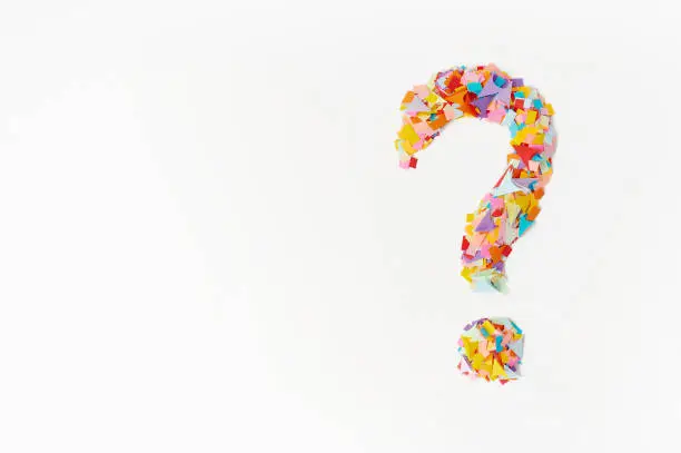 Photo of question mark on a  background from multi-colored confetti, from pieces of color paper.