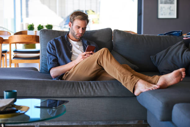 istock caucasian man busy texting while sitting in a modern home 985458346
