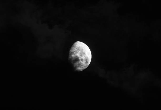 gorgeous moon in a dark blue night sky gets covered by soft wispy dark clouds A gorgeous moon in a dark blue night sky gets covered by soft wispy dark clouds apollo 11 stock pictures, royalty-free photos & images