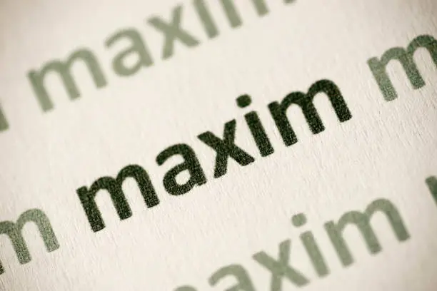 word maxim printed on white paper macro