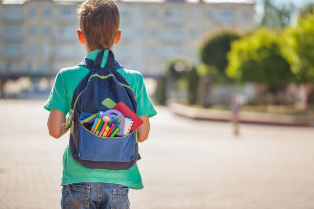 istock Schoolboy with full backpack go to school. Back view 985517728