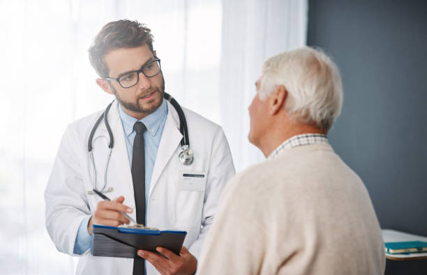 Let's set up an appointment for next week Cropped shot of a young male doctor going through medical records with his senior male patient doctor consultation stock pictures, royalty-free photos & images