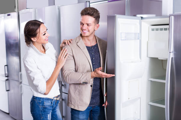 istock young positive couple choosing new refrigerator in hypermarket 985554612