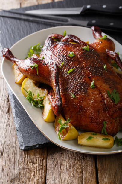 istock Delicious whole baked duck with apples close-up on a platter. vertical 985570286