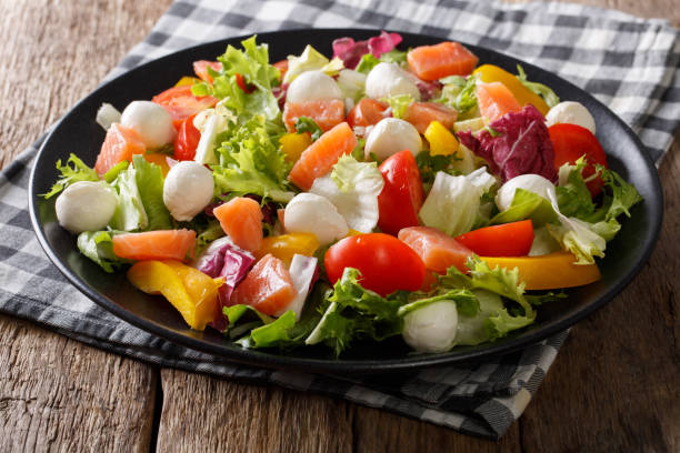 istock Spicy salad with salmon, mozzarella and fresh vegetables close-up on a plate. horizontal 985577876
