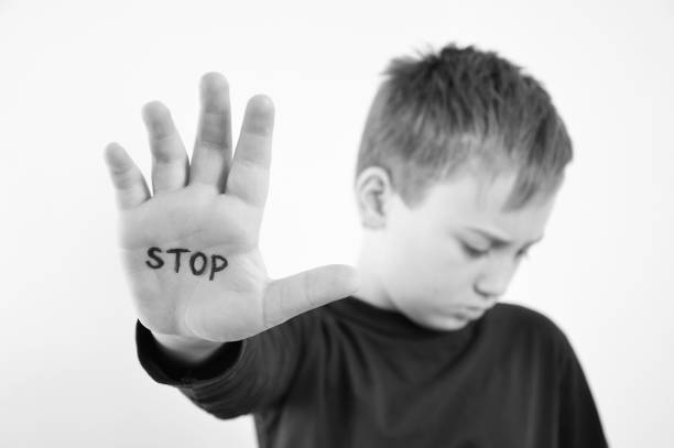 Small abused boy holding his hand with the word 'STOP' written on it. Concept of domestic violence and child abusement.