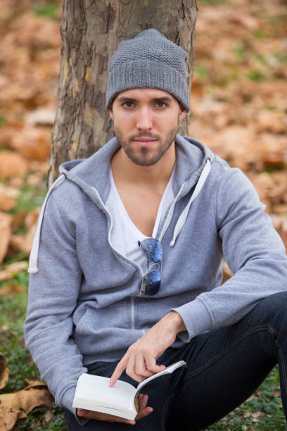 istock Handsome man in nature reading a book. Autumn leaves. Copy space 985597550