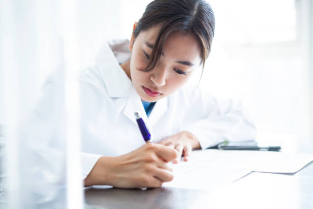 istock A woman working in a white coat is writing. 985602512