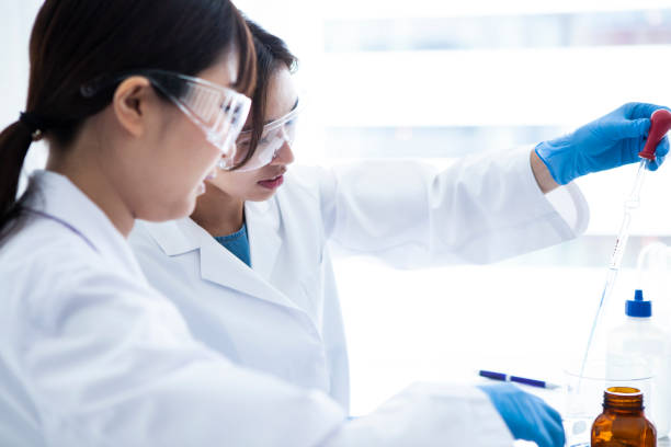 istock A woman wearing protective equipment which is experimenting with liquid. 985605234