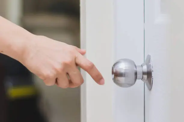 Photo of close up of woman’s hand reaching to door knob, opening the door