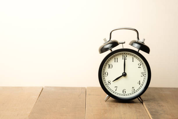istock black vintage alarm clock close to the window present eight o'clock 985606908
