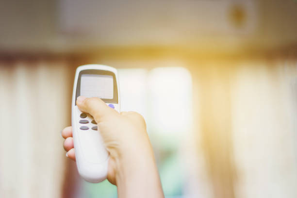 istock Air conditioner inside the room with woman operating remote controller 985607148