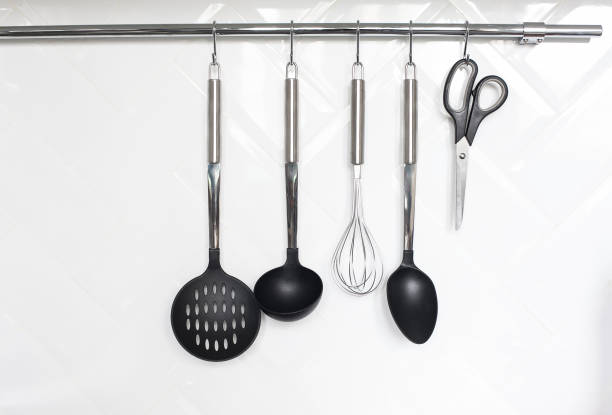 Set of cutlery hanging on white wall in the kitchen