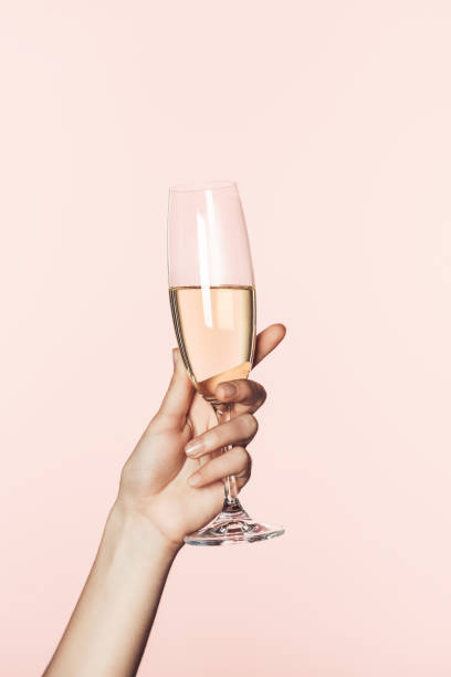 обрезанный выстрел женщины аплодисменты бокал шампанского изолированы на розовом фоне - pink champagne стоковые фото и изображения