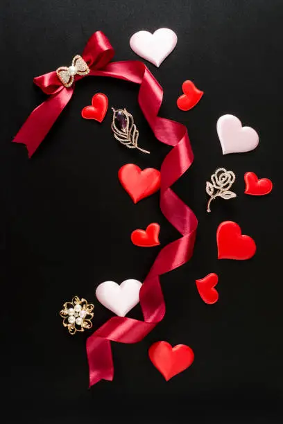Composition with brooches, bow and ribbon on a black background