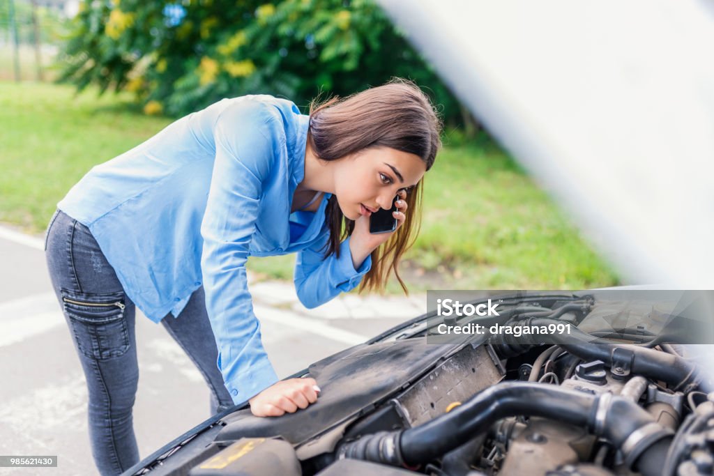 Car problems Calling Emergency Service. Car problems. Young woman using mobile phone while looking at broken down car on street. Woman caling autoservice because of car problem Car Stock Photo