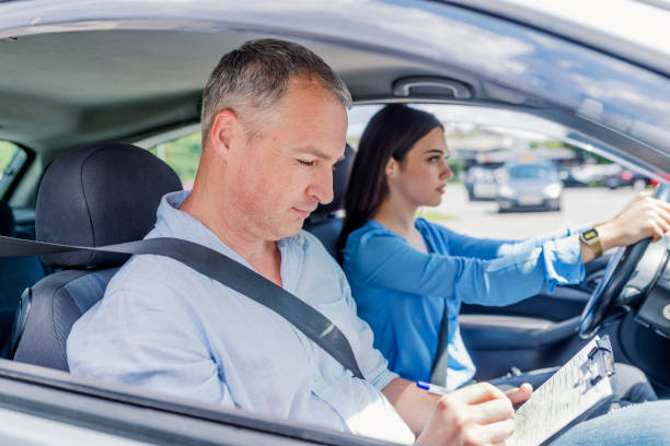 istock Instructor of driving school giving exam while sitting in car 985629444