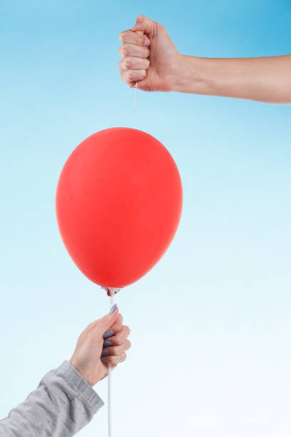 istock hand holding needle near balloon. isolated on white. Danger concept. 985629670