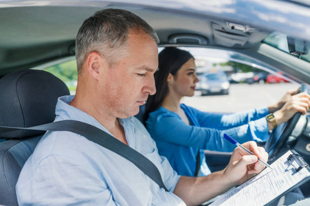 istock Driving instructor and woman student in examination car 985629842