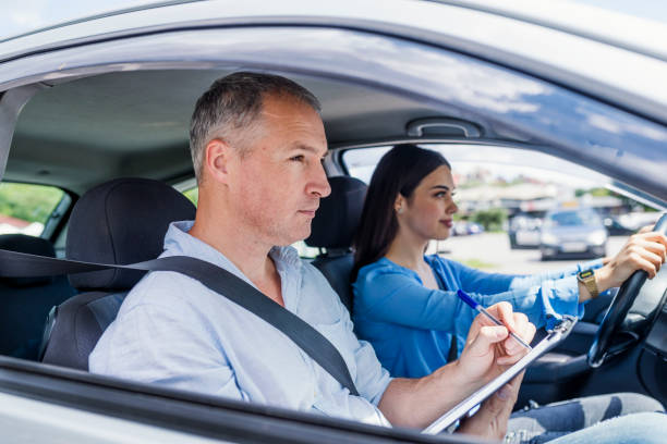 giovane donna in un test di guida con il suo istruttore - car insurance women driving foto e immagini stock