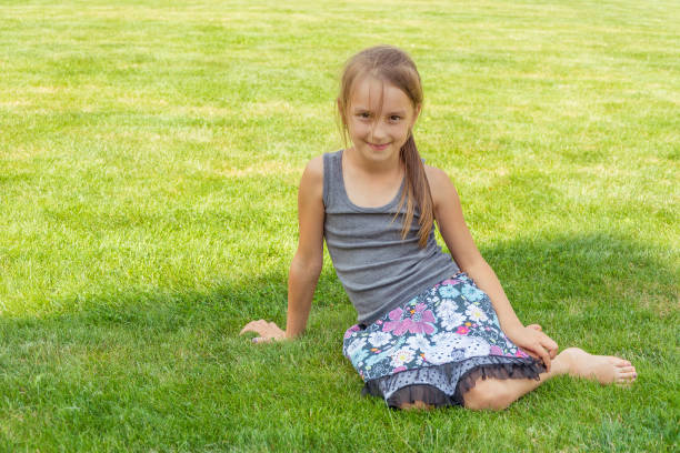 Child girl sitting in grass in shadow during summer