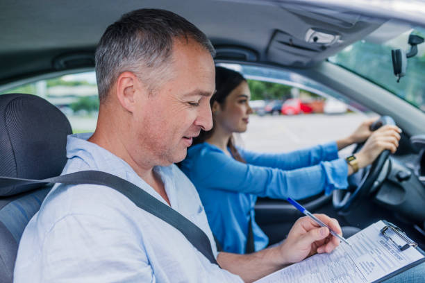 Learning to drive a car Young woman on a driving test with her instructor. Learning to drive a car. Driving school. Instructor of driving school giving exam while sitting in car driving test photos stock pictures, royalty-free photos & images