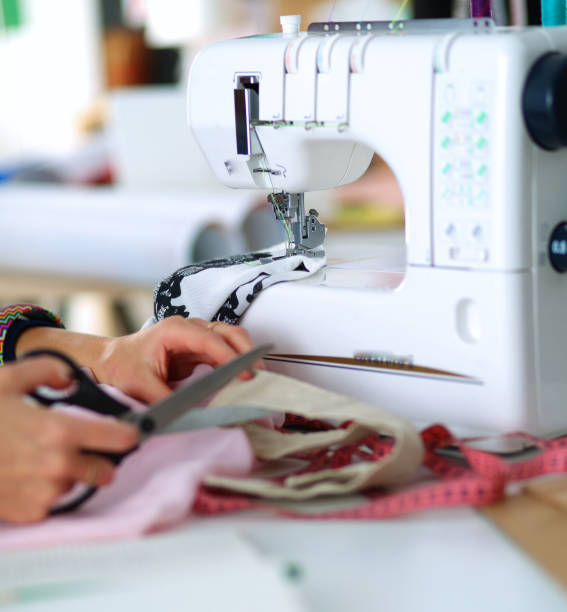 istock Young woman sewing while sitting at her working place 985633114