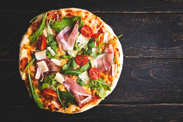 Pizza with tomatoes, mozzarella cheese ham and arugula.