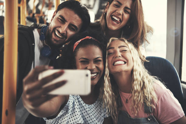 istock Laughing group of friends taking selfies together on a bus 985664228