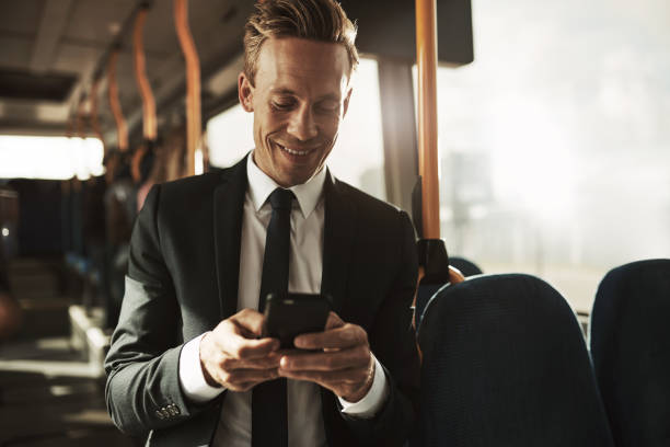 istock Smiling young businessman reading text messages during his morning commute 985665638