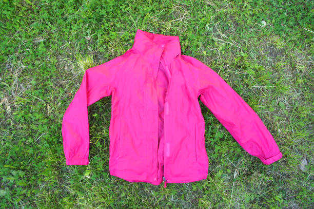 istock women's raincoaton on grass background. pink. top view. 985666966