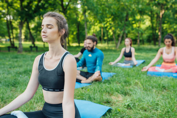 istock Young woman doing breathing exercises at the park 985671198