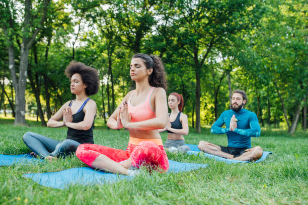 instruktor jogi ćwiczący ze sportowcami w parku - zen like nature breathing exercise sitting zdjęcia i obrazy z banku zdjęć