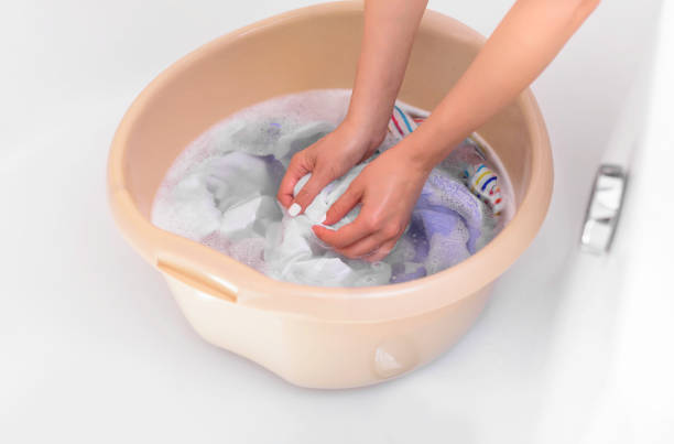 istock Women's hands wash clothes in the basin. 985680190