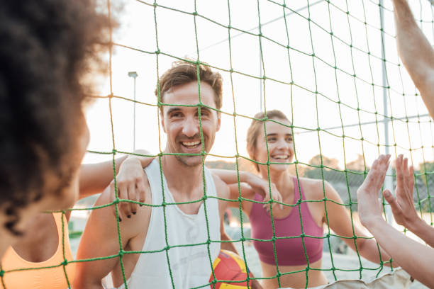 istock Happy man looking at his team mates through the volleyball net 985682908