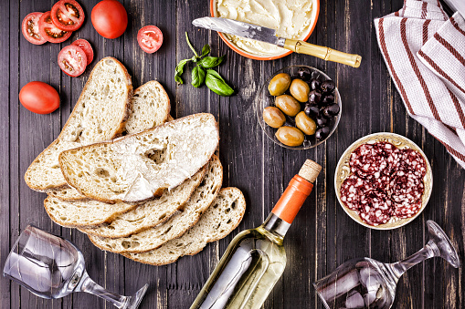 Wine snack set. Italian snacks on a wooden background with wine. Whole salami, ciabatta and different types of olives. Traditional Mediterranean table. top view