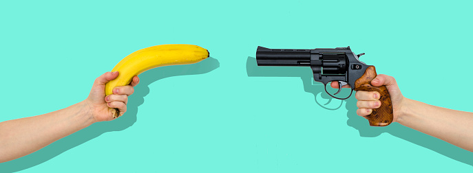 hand with a banana and a hand with gun