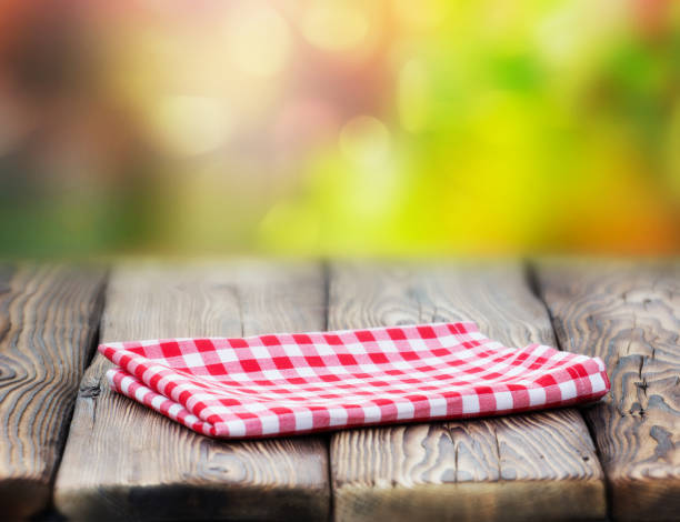 istock Red picnic cloth on wooden table mature bokeh background. 985763616
