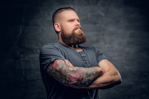 istock Bearded male with tattooed crossed arms. 985778156