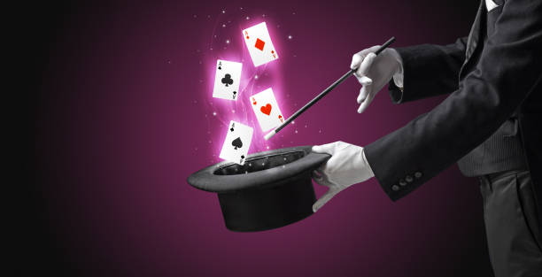 istock Magician making trick with wand and playing cards 985778266