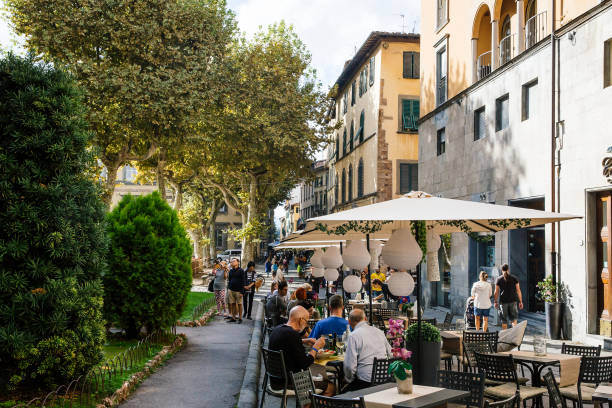 People enjoy their meals in cafe LUCCA, ITALY - OCTOBER 5, 2017: Tourists on the streets of ancient medieval town. People enjoy their meals in cafe.Typical touristic city life scene. lucca italy stock pictures, royalty-free photos & images