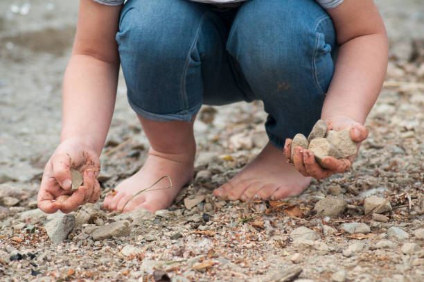 istock feet of child playing on the beach with stone 985784672