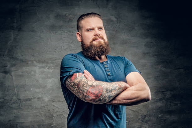 Bearded fat male with tattoo on arms. Bearded fat male with tattoo on arms posing over grey background. chest tattoos for men designs stock pictures, royalty-free photos & images