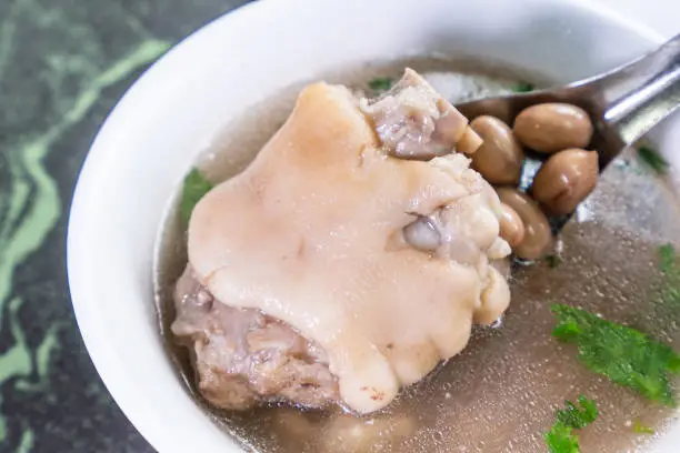 Photo of Taiwan's distinctive famous snacks: Peanut pork knuckle(pig's trotter) soup in a white bowl on stone table, Taiwan Delicacies, Taiwan Street Food